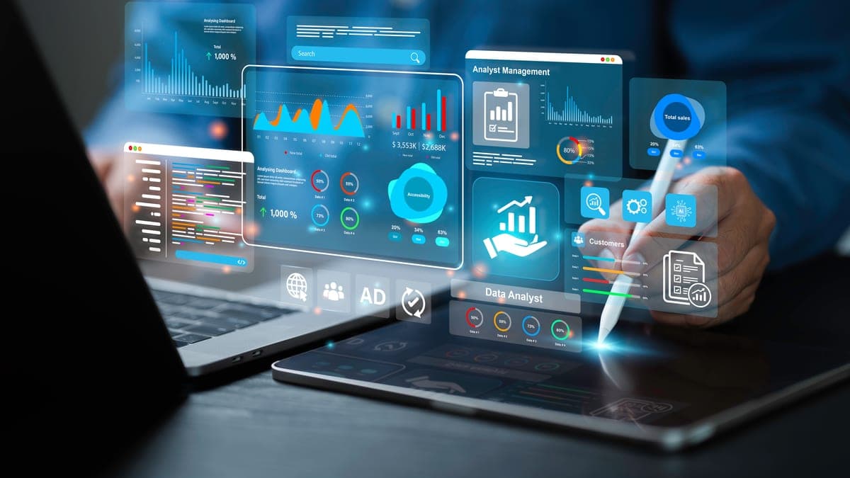 Analyst arbeitet mit Stift an holografischen Dashboards über Laptop und Tablet, Sinnbild für KI-gestützte Auswertung von Gesprächen