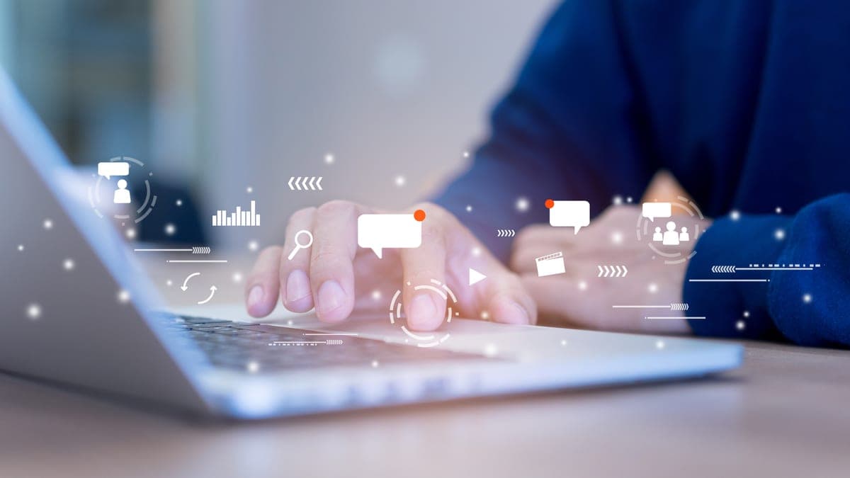 Hände tippen auf einem Laptop, darüber schweben Chat- und Kommunikations-Symbole, Sinnbild für Team-Kommunikation im Verein