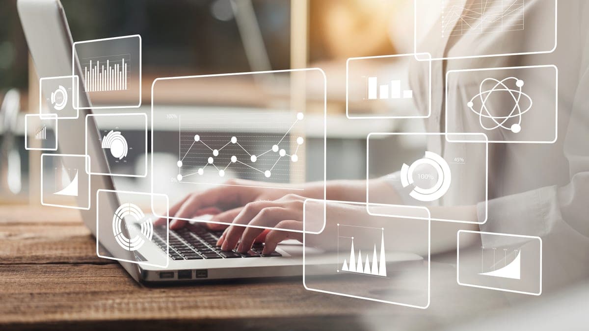Hände tippen auf einem Laptop mit schwebenden Dashboard-Fenstern und Kennzahlen, Sinnbild für digitale Zeiterfassung